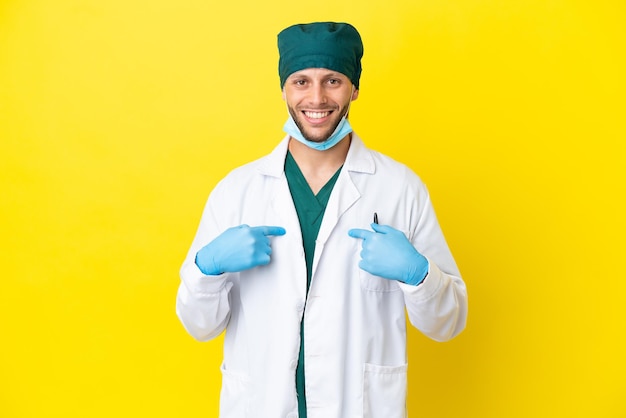 Chirurg blonde man in groen uniform geïsoleerd op gele achtergrond met verrassing gezichtsuitdrukking
