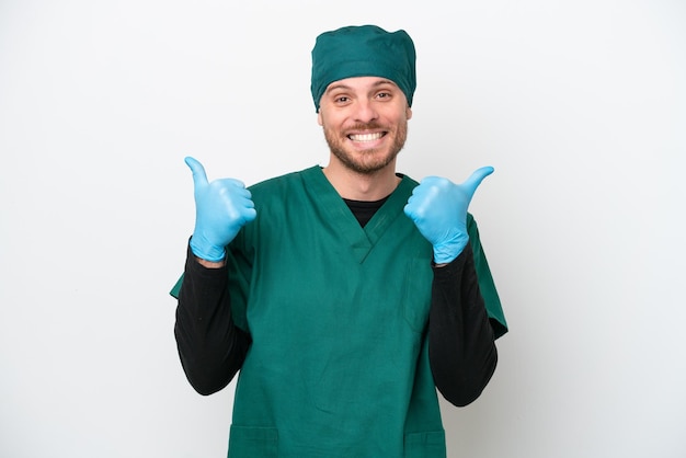 Chirurg Braziliaanse man in groen uniform geïsoleerd op een witte achtergrond met duim omhoog gebaar en lachend