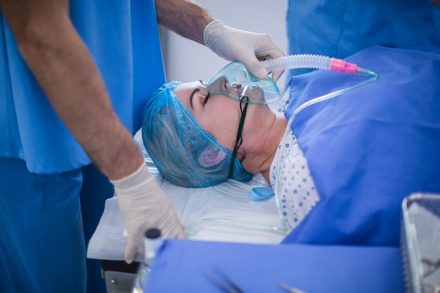 Chirurg die zuurstofmasker op een patiënt zet