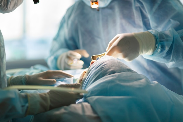 Chirurg en assistent uitvoeren van cosmetische chirurgie op neus in operatiekamer