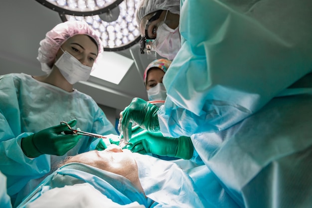 Chirurg en zijn assistent voeren cosmetische chirurgie uit aan de neus in de operatiekamer van het ziekenhuis Neus hervormende augmentatie Neuscorrectie