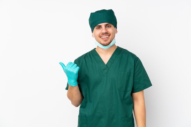 Chirurg in groen uniform op witte muur wijst naar de zijkant om een product te presenteren