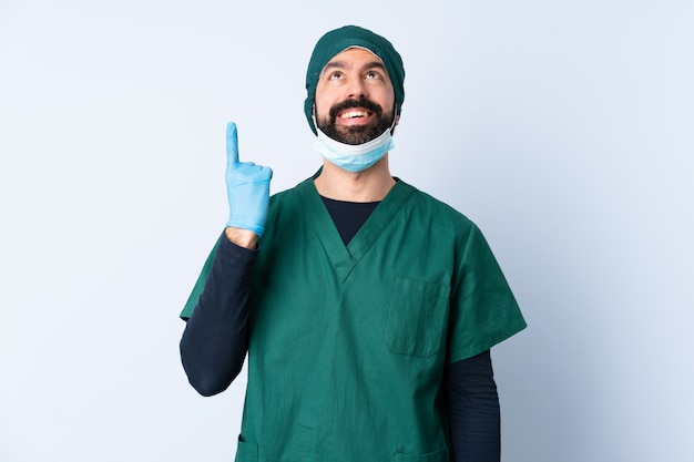 Chirurg man in groen uniform over geïsoleerde muur naar boven en verrast
