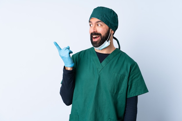 Chirurg man in groen uniform over muur met de bedoeling de oplossing te realiseren terwijl hij een vinger opheft