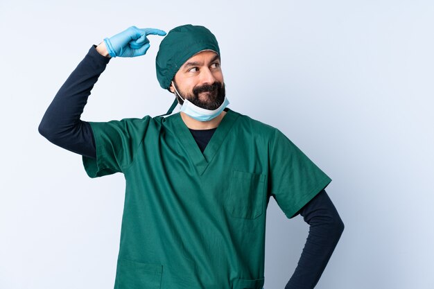 Chirurg man in groen uniform over muur twijfels tijdens het krabben van het hoofd