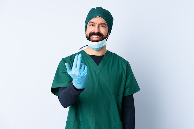Chirurg man in groen uniform over muur uitnodigend om met de hand te komen.