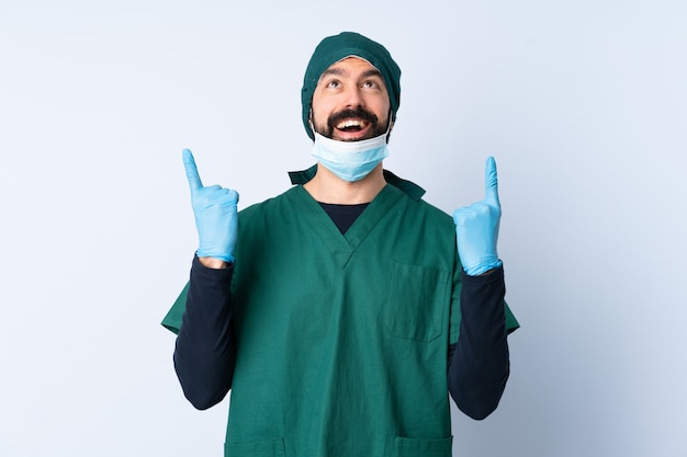 Chirurg man in groen uniform over muur verrast en omhoog