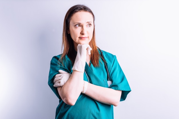 Chirurg met stethoscoophandschoenen en operatiekamerkleding kijkt naar de zijkant peinzend .medicine concept