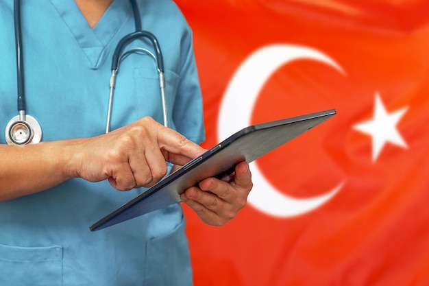 Chirurg of arts met behulp van een digitale tablet op de achtergrond van de vlag van Turkije