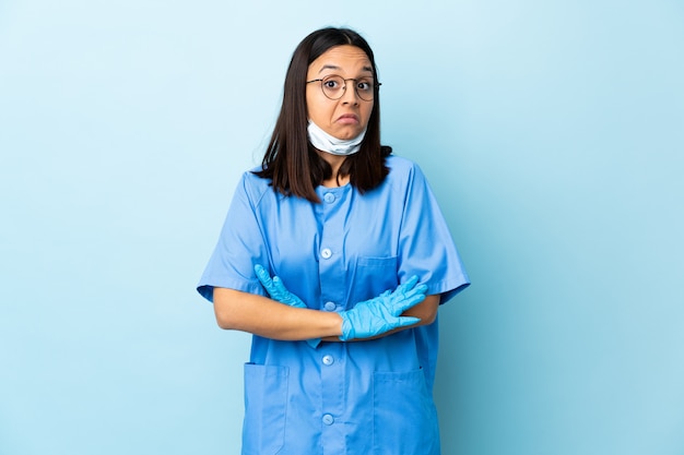 Chirurg vrouw over blauwe muur twijfels gebaar maken terwijl het opheffen van de schouders