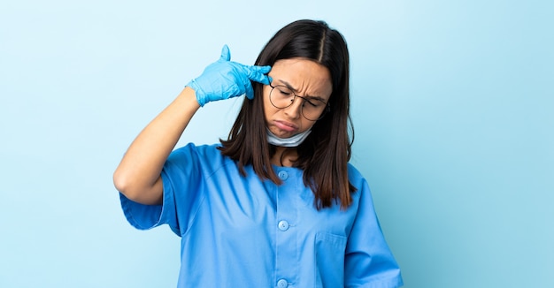 Chirurg vrouw over geïsoleerde blauwe muur met problemen die zelfmoordgebaar maken