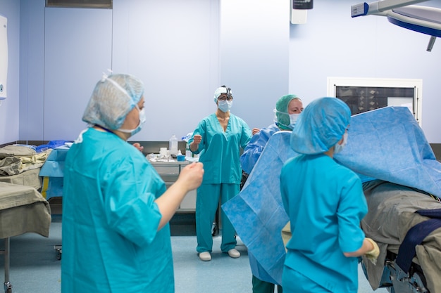 Foto chirurgie, geneeskunde en mensenconcept - groep chirurgen in operatiekamer bij het ziekenhuis die en aan verrichting spreken voorbereidingen treffen