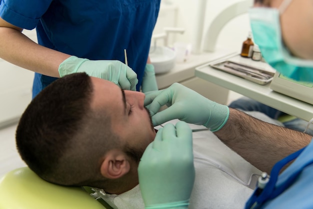 Chirurgie in de tandartspraktijk Dokter werkt aan de mond van de patiënt met de hulp van een assistent