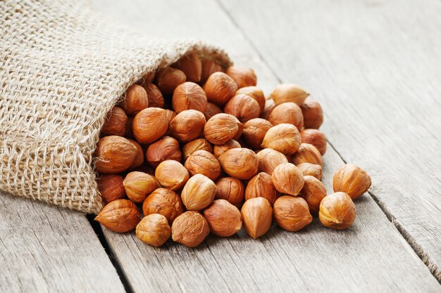 Chiselled hazelnuts in a bag of burlap on a gray wooden table. Organic Fresh Harvested