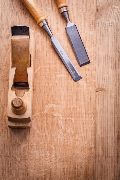 Photo chisels and woodworkers plane on wooden board construction concept