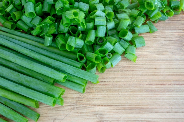 Chives whole and cut on a wooden board