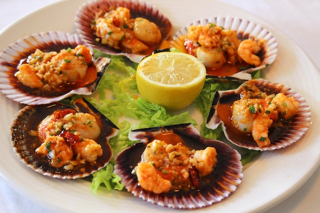 Chlamys varia or scallop cooked on the grill with a lemon slices