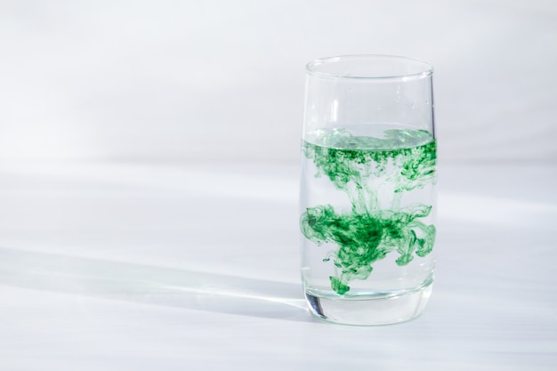 Chlorophyll in glass of water. Copy space, sunlight.