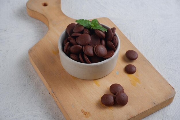 choco chips or chocolate morsels in white bowl on texture white backgroundisolated