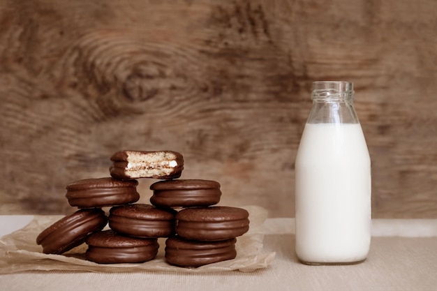 Шоколадный пирог, закуски в шоколаде и бутылка молока на деревянном фоне Десерт с молоком Сладкие закуски Коричневые цвета
