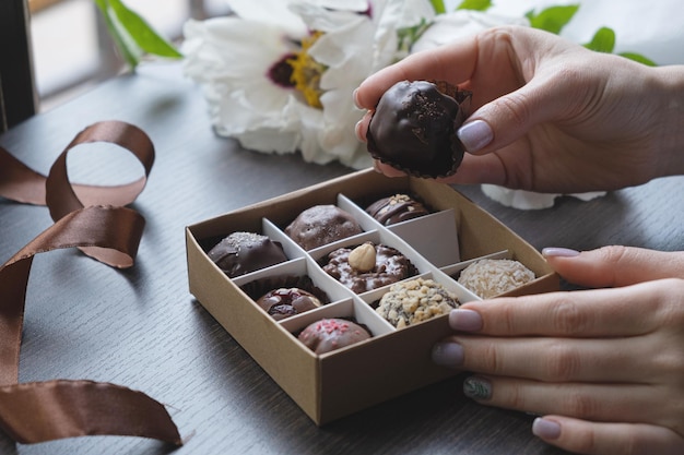 Chocolade ambachtelijk snoep in vrouwelijke hand en geschenk snoepdoos