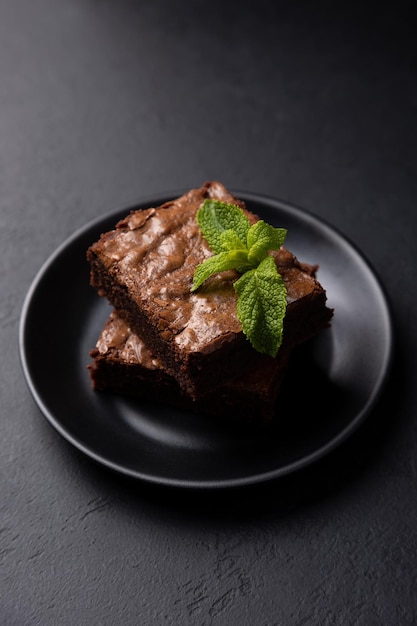 Chocolade brownie cake met mint Traditioneel Amerikaans dessert Populaire cake met pure chocolade op een zwarte achtergrond Close-up selectieve aandacht