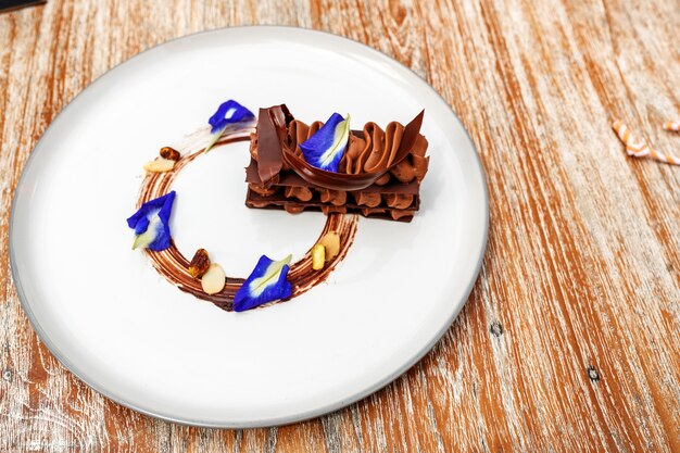Chocolade brownie versierd met blauwe bloemen op een bord