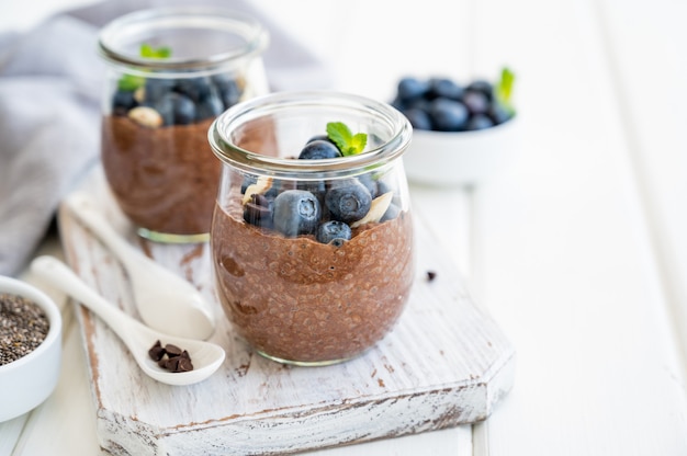 Chocolade chia pudding met bosbessen, amandelen en munt in een glazen pot