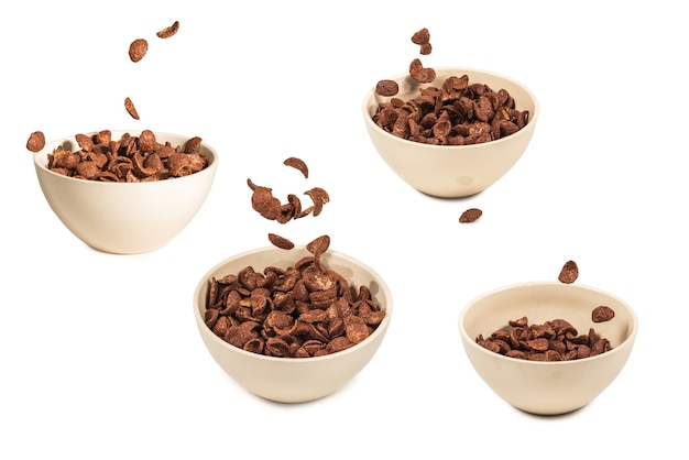 Chocolade cornflakes vallen op de witte kom geïsoleerd op wit. Beweging. Kopieerruimte.