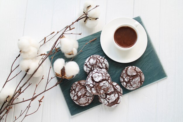 Chocolade crinkle brownie cookies in suikerpoeder naast kopje koffie bovenaanzicht