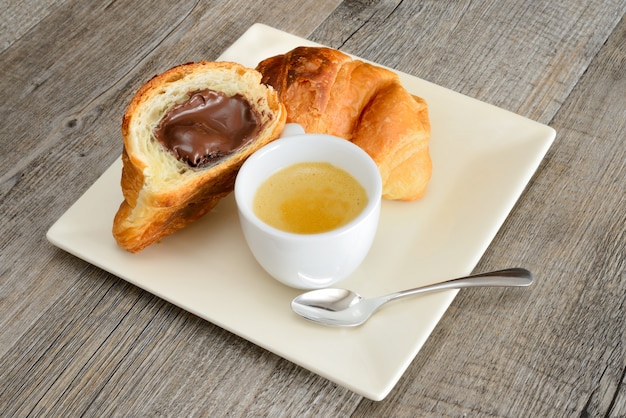 Chocolade croissant met slagroom voor het ontbijt en een kopje koffie