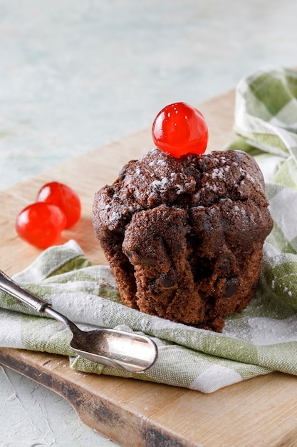 Chocolade cupcake met suikerglazuur op servet op houten raad en oude lepel