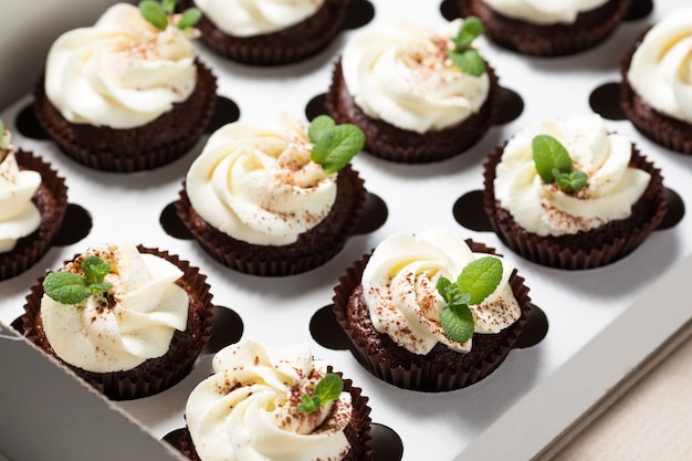 Chocolade cupcakes met kaascrème en muntblaadjes in leveringsdoos