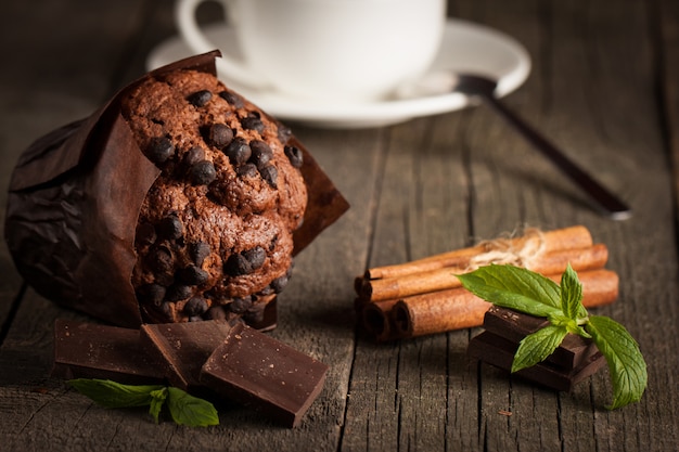 chocolade donkere gekookte muffin met munt op een houten tafel met kaneel, anijs, chocolade.