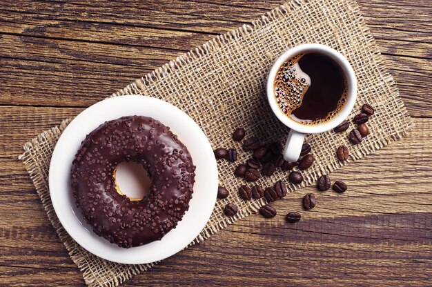 Chocolade donut en kopje koffie op houten tafel