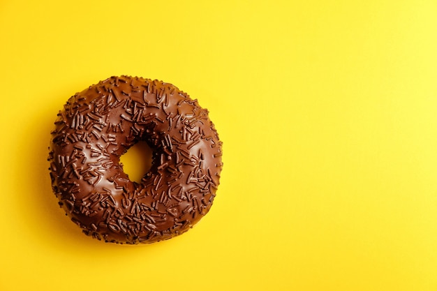 Chocolade donut op gele achtergrond bovenaanzicht
