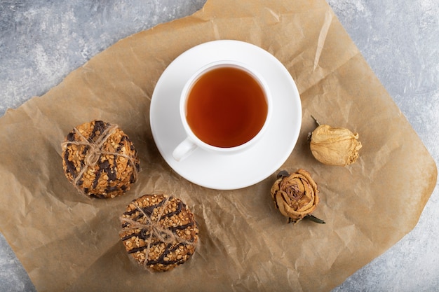 Chocolade gecoate havermoutkoekjes en een kopje thee op een stenen tafel.