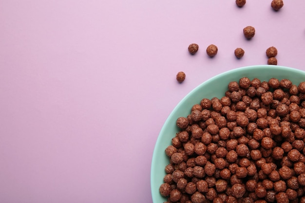 Chocolade granen maïs ballen in een blauwe kom op een paarse achtergrond