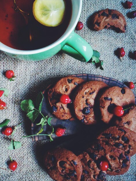 Foto chocolade havermout koekjes een kop zwarte thee met citroen en wilde roos bessen op tafel