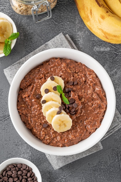 Chocolade havermoutpap met banaan en chocoladeschilfers bovenop Gezond ontbijt Kopieer de ruimte