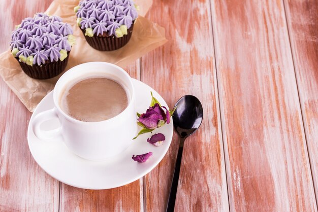 Chocolade heerlijke cupcake met room en geurige koffie met melk op een witte houten tafel.