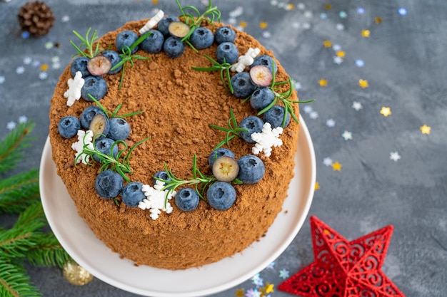 Chocolade-honingcake met bosbessen, rozemarijn en suikersneeuwvlokken Taart voor Kerstmis en Nieuwjaar