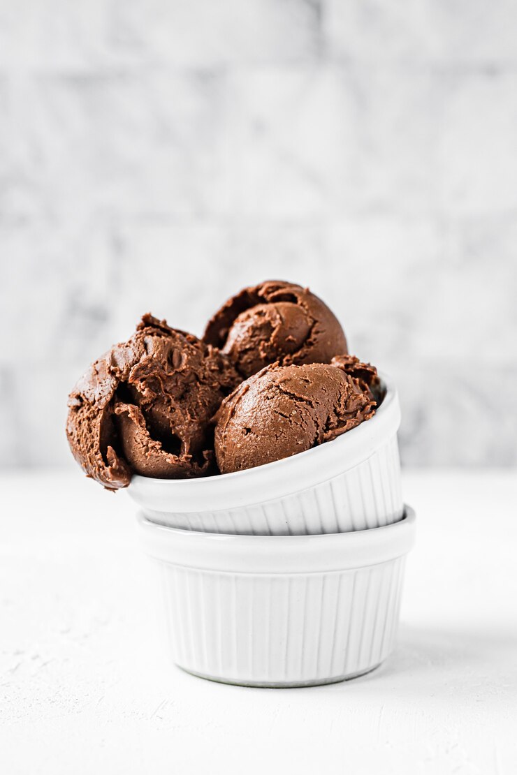 Chocolade-ijsballen in twee witte kommen, lichte en heldere achtergrond