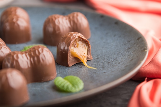 Chocolade karamel snoep met amandelen en een kopje koffie op een zwarte betonnen ondergrond. zijaanzicht, selectieve aandacht.