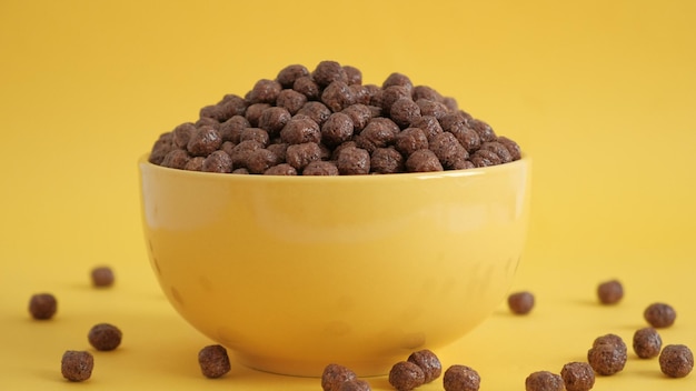 Chocolade maïs ballen in een gele kom op een gele achtergrond. Ontbijt eten concept