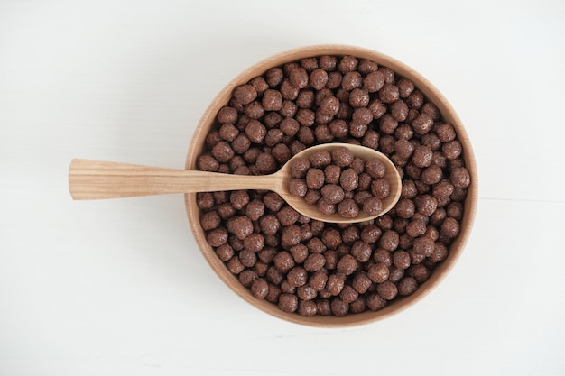 Chocolade maïs ballen in een houten kom en lepel op een witte achtergrond