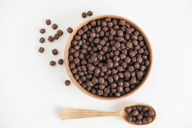 Chocolade maïs ballen in een houten kom en lepel op een witte achtergrond