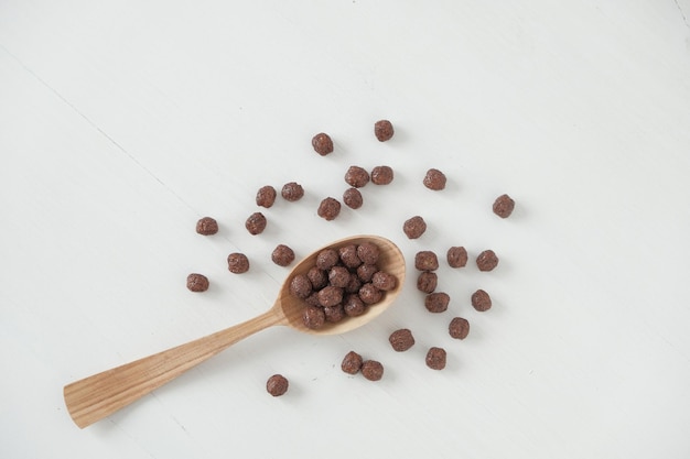 Chocolade maïs ballen in een houten lepel verspreid op een witte achtergrond