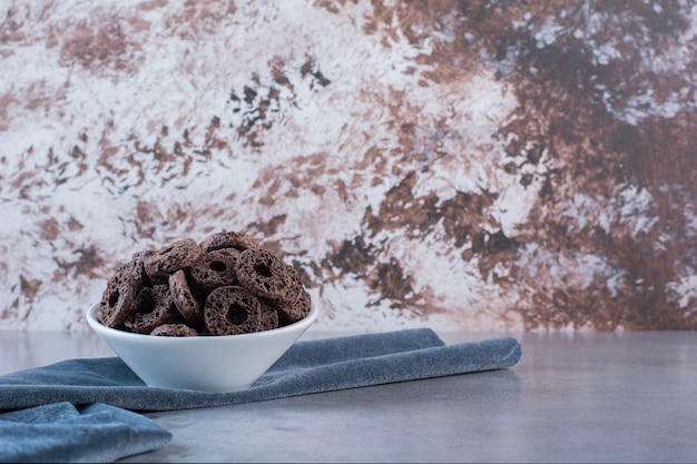 Chocolade maïs ringen geïsoleerd op een witte plaat op een stenen oppervlak