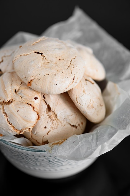 Chocolade meringue ligt op een zwarte tafel Meringue in een kom Glanzend zwarte tafel